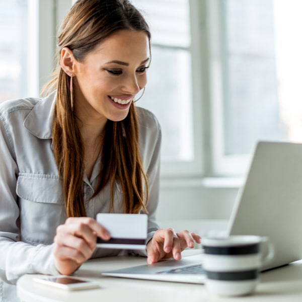 Vrouw winkelt online op haar laptop en houdt een betaalkaart vast